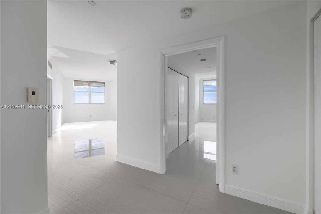 Interior space featuring polished tile flooring, white walls, and floor-to-ceiling closets with sliding panel doors