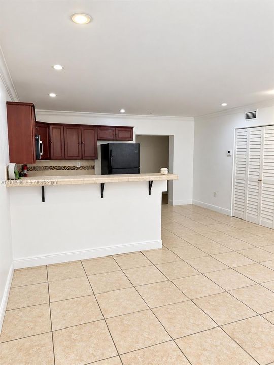 Kitchen featuring wood cabinetry, tiled countertops, a breakfast bar, recessed lighting, and tile flooring