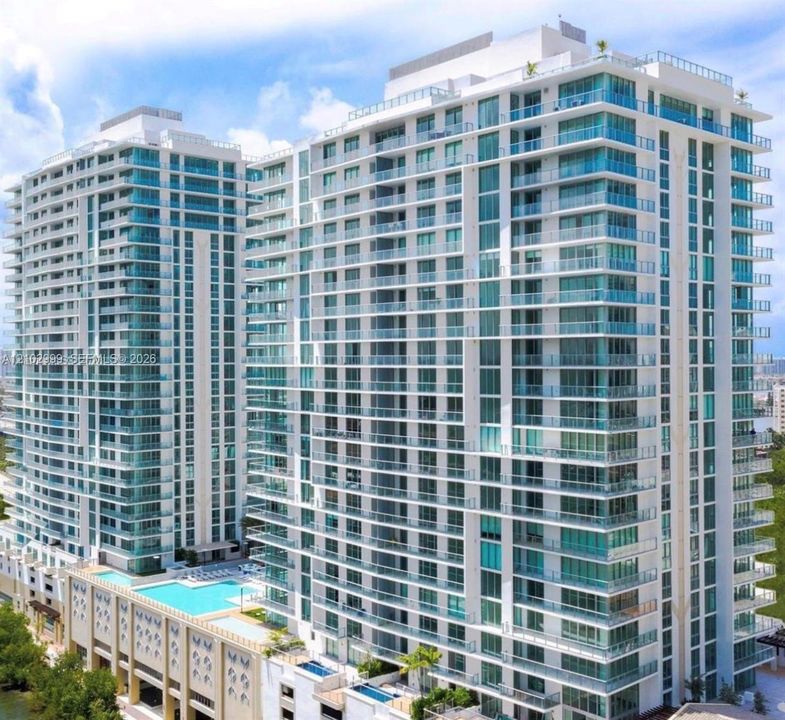 Modern high-rise residential building featuring multiple levels of balconies with glass railings