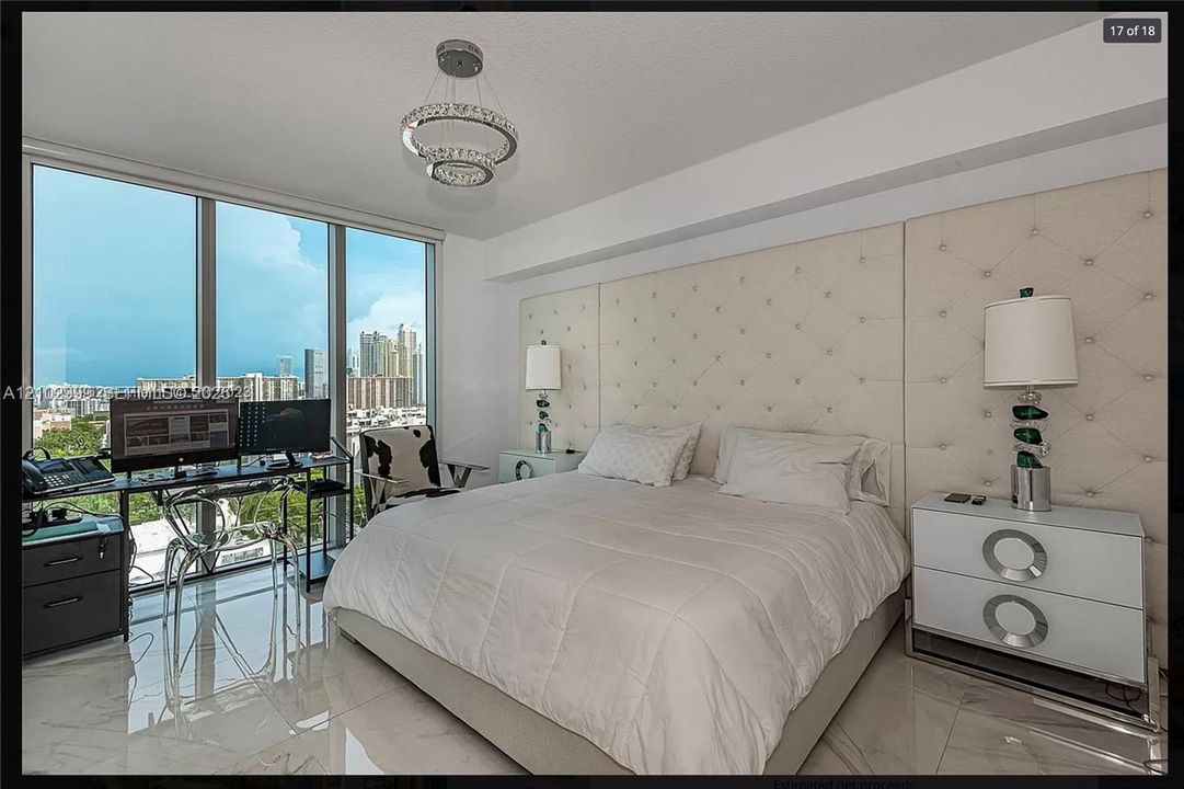 Floor-to-ceiling windows, polished tile flooring, recessed lighting, and a tufted upholstered wall panel
