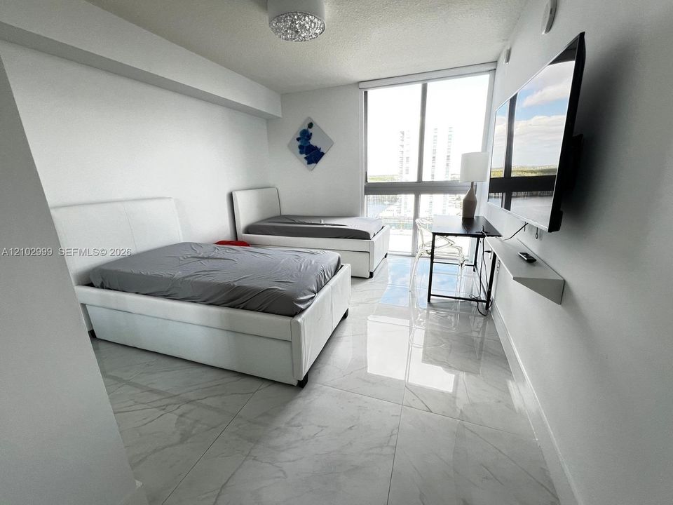 Floor-to-ceiling windows, polished stone-finish flooring, wall-mounted floating shelf, and contemporary flush-mount ceiling lighting