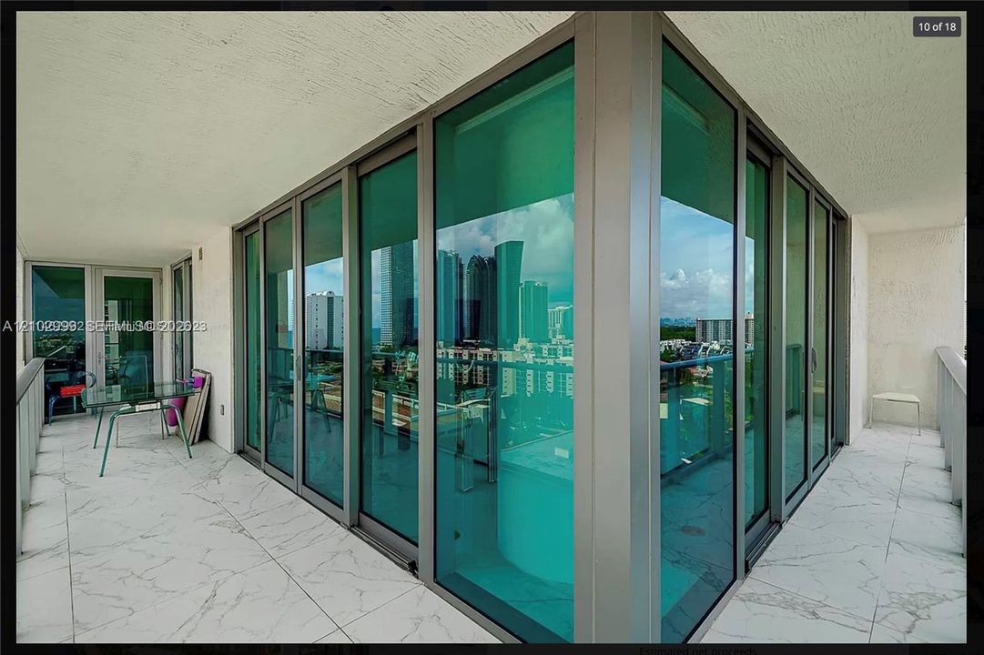 Wraparound balcony featuring floor-to-ceiling glass paneling, metal railings, and large-format tile flooring