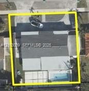 Aerial perspective of a property lot featuring a single-story structure, a paved driveway, and an in-ground swimming pool