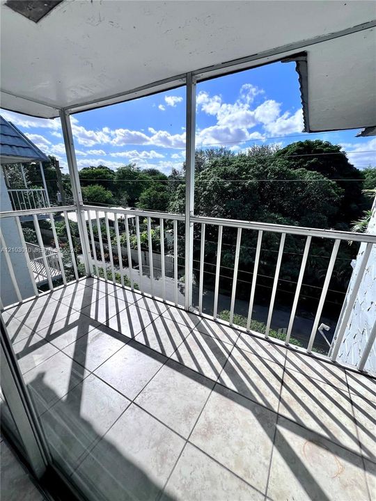 Screened balcony featuring white aluminum railings, tiled flooring, and a covered ceiling