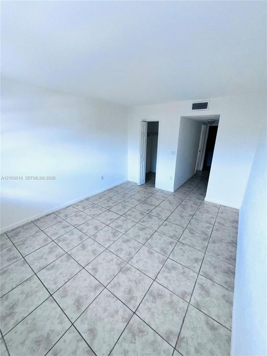 Interior space featuring neutral wall tones, large-format ceramic tile flooring, and a walk-in closet with double-panel doors