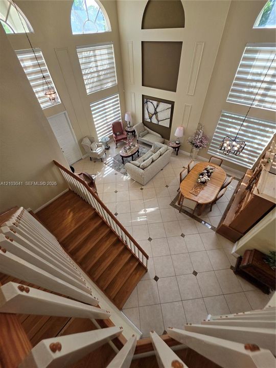 Two-story architectural design with high ceilings, arched windows, and a hardwood staircase