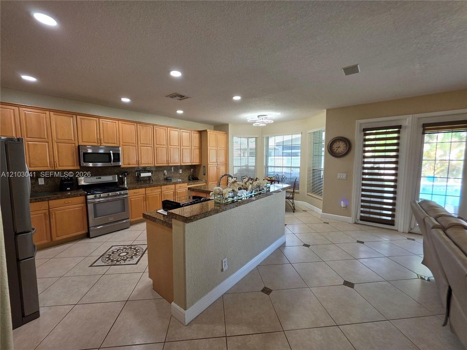 Kitchen featuring wood cabinetry, stainless steel appliances, a center island with a breakfast bar, and tile flooring