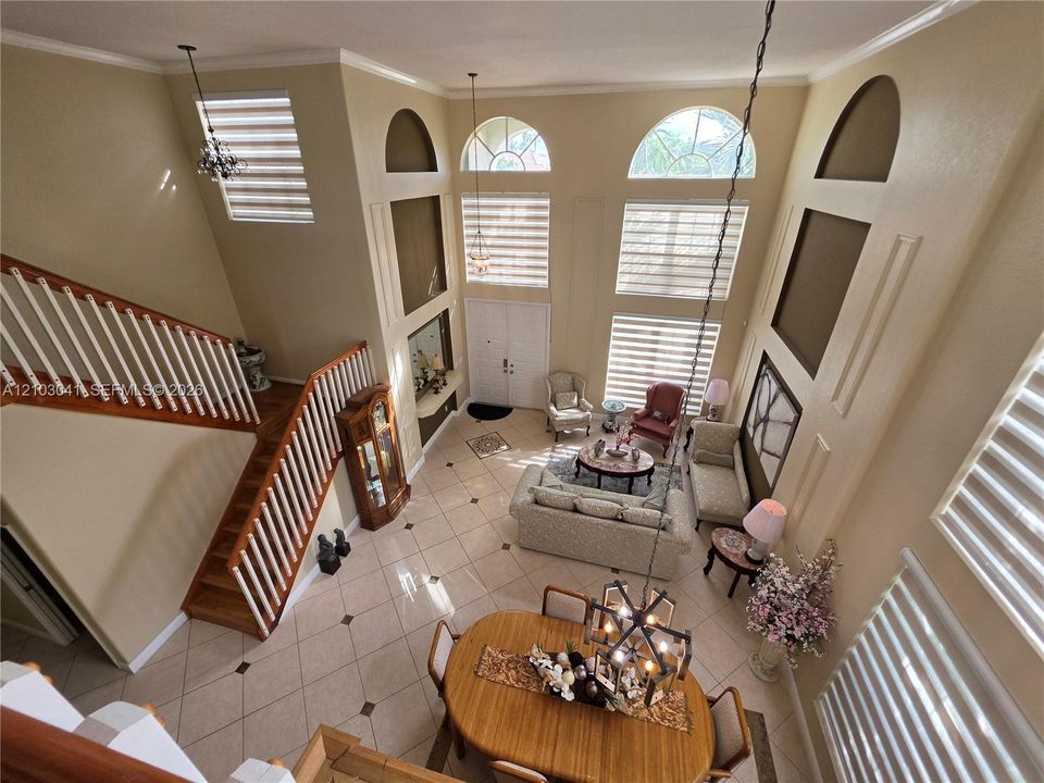 Two-story entry with a wood staircase, arched windows, and tile flooring
