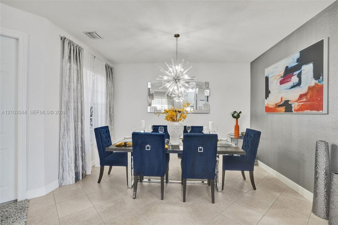 Dining space featuring oversized ceramic tile flooring, a neutral color palette with a grey accent wall, and a multi-spoke sunburst-style overhead light fixture