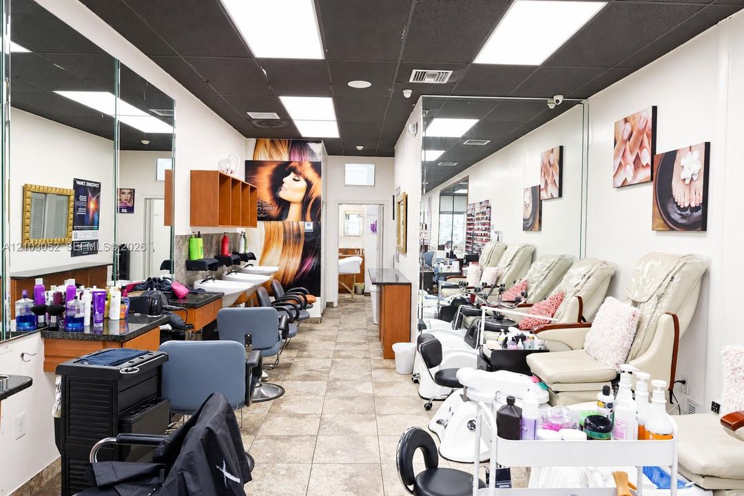 Commercial space featuring tile flooring, full-wall mirrors, drop ceiling with integrated recessed lighting, and multiple built-in wash stations with stone-finish countertops