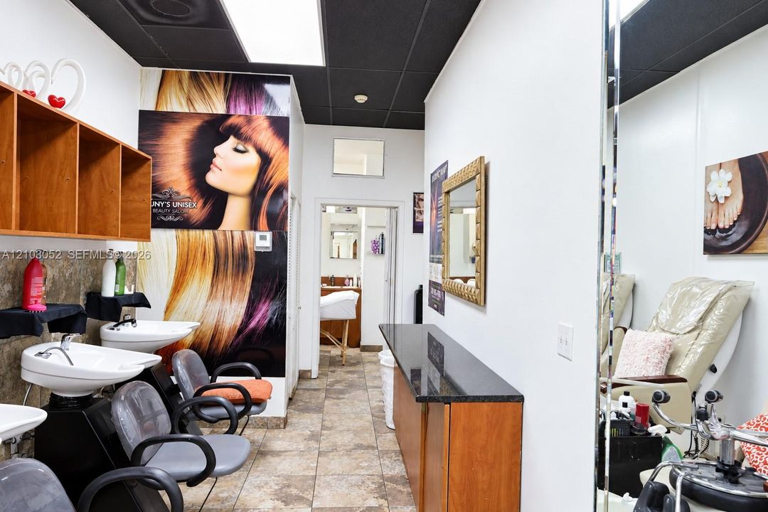 Commercial space featuring tile flooring, built-in cabinetry with stone-finish countertops, wall-mounted sinks, and a drop ceiling