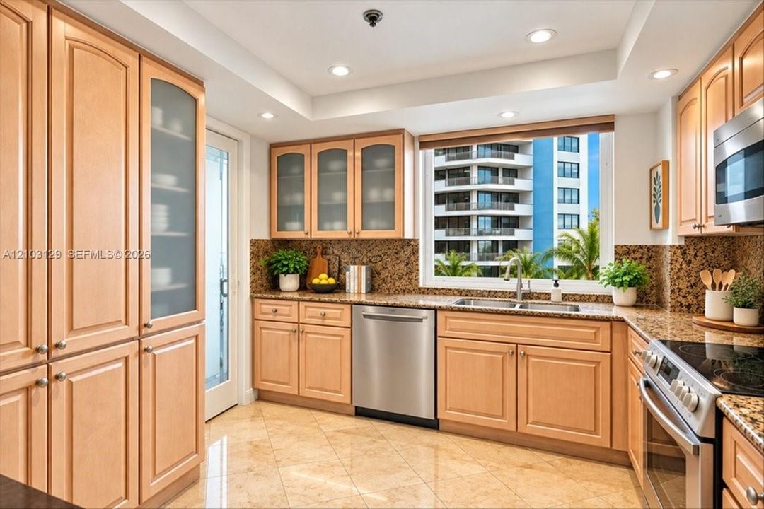 Kitchen featuring light wood cabinetry with glass-front uppers, stone countertops and backsplash, tile flooring, recessed lighting, and stainless steel appliances