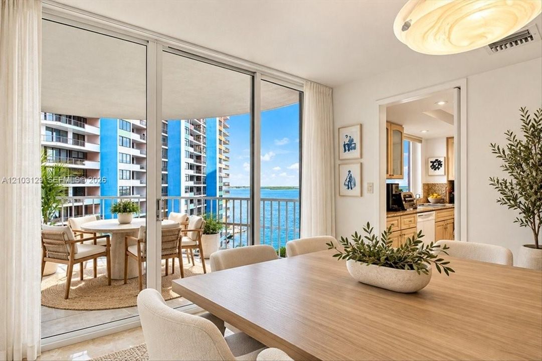 Floor-to-ceiling sliding glass doors, private balcony with metal railing, water frontage, and light-toned tile flooring