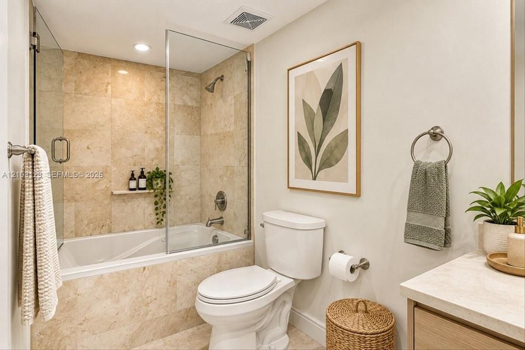 Full-height natural stone tile shower surround, frameless glass door, built-in stone recessed shelving, and a stone-topped vanity