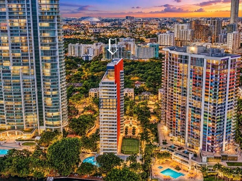 High-rise tower featuring a distinctive red facade, rooftop terrace, onsite tennis court, and ground-level pool