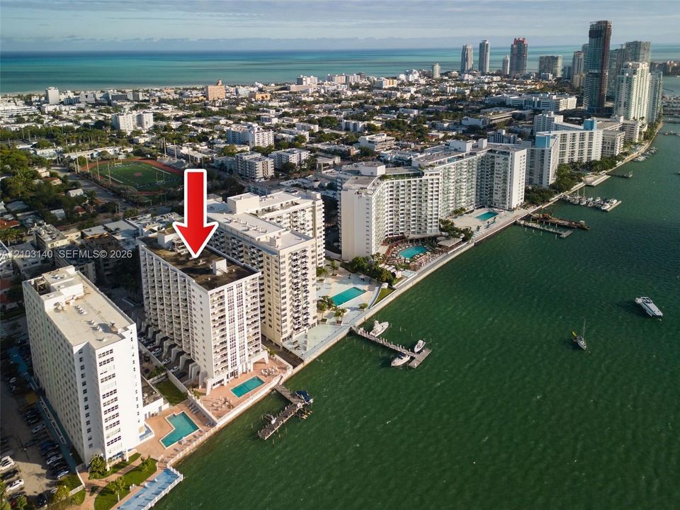 High-rise residential building featuring exterior balconies, a waterfront swimming pool, and private boat dockage