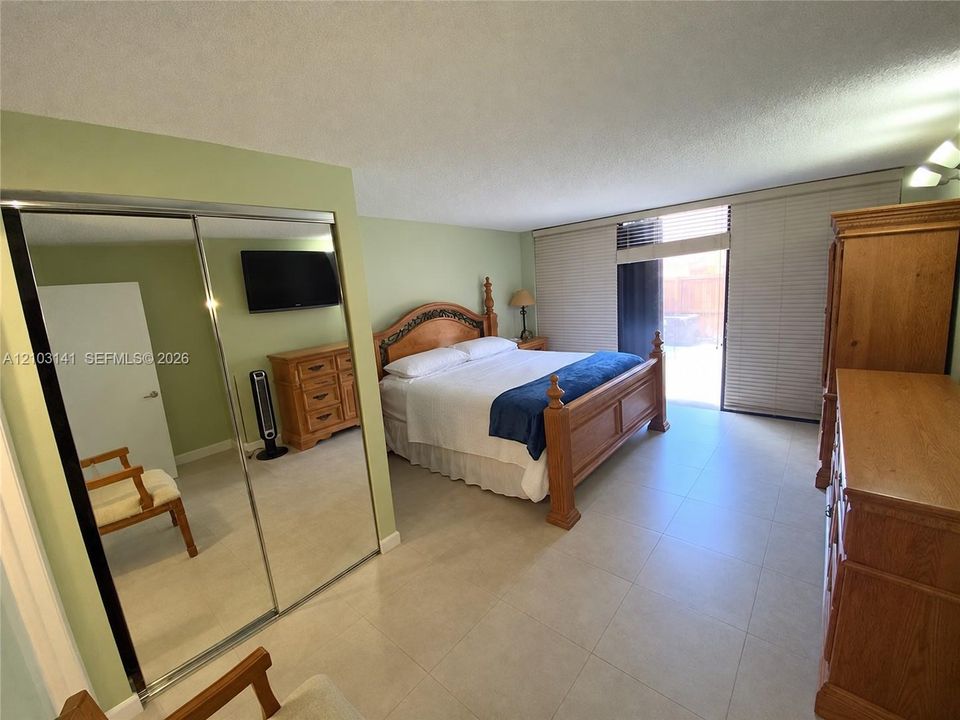 Large sliding mirror closet doors, light-colored floor tiling, and a sliding glass door with integrated horizontal blinds