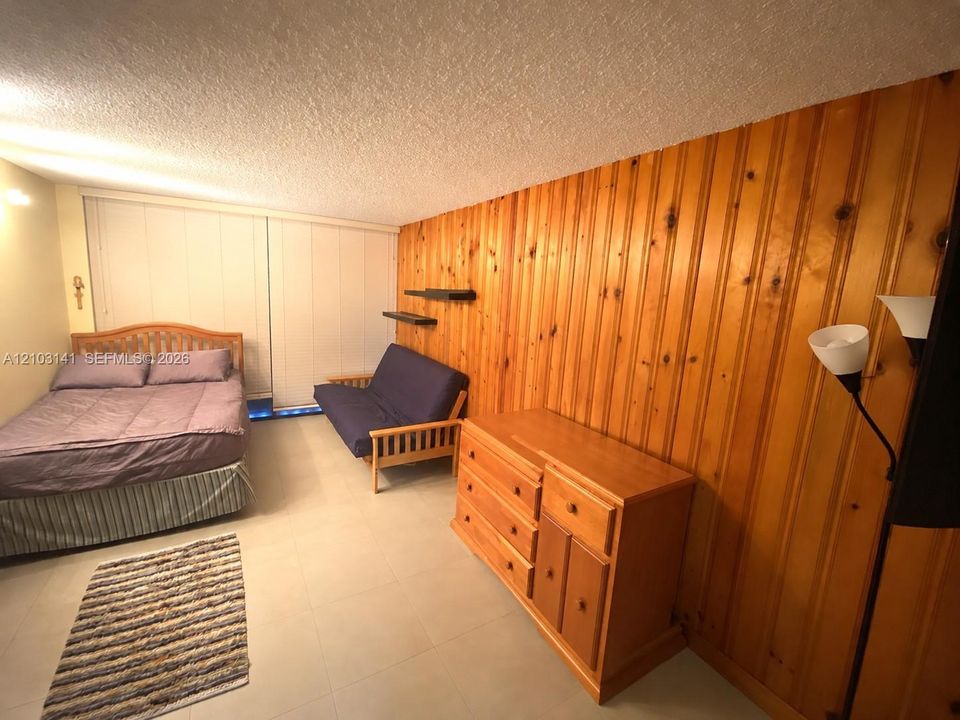 Vertical wood-plank paneled feature wall, tile flooring, and wall-mounted shelving