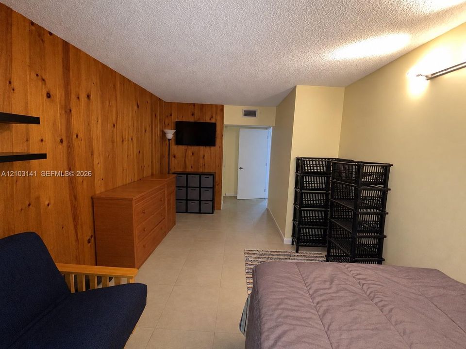 Interior space featuring wood-panel accent wall and neutral tile flooring