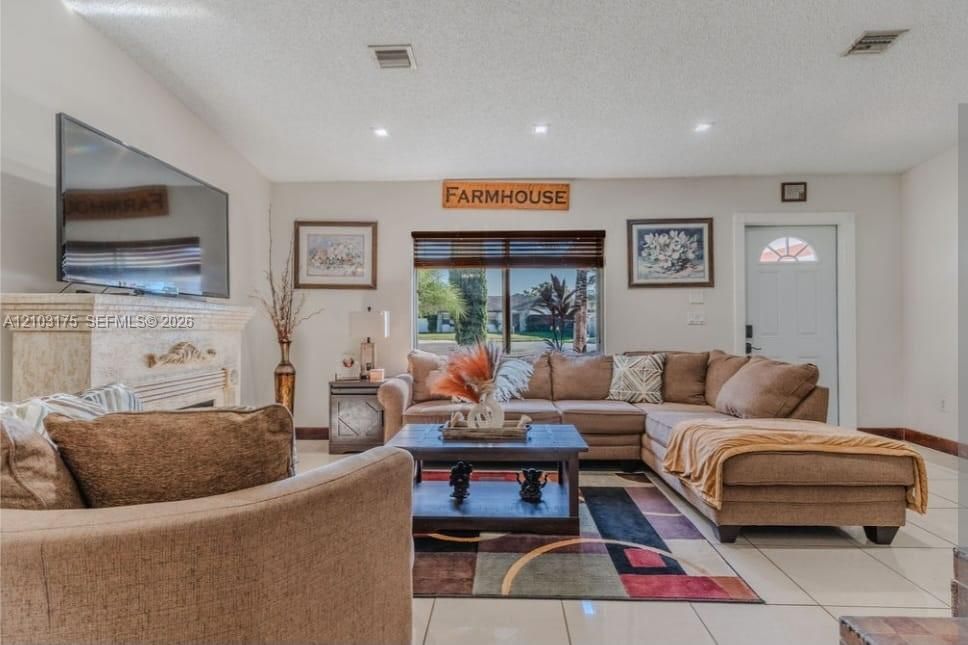 Living area featuring tile flooring, a stone-surround fireplace, recessed lighting, and a window with horizontal blinds
