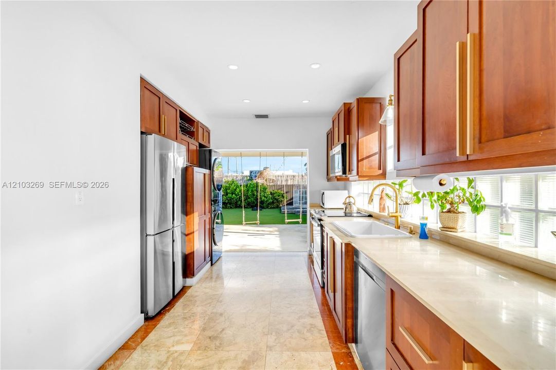 Kitchen featuring wood cabinetry, stone-finish countertops, stainless steel appliances, a farmhouse-style sink, and recessed lighting
