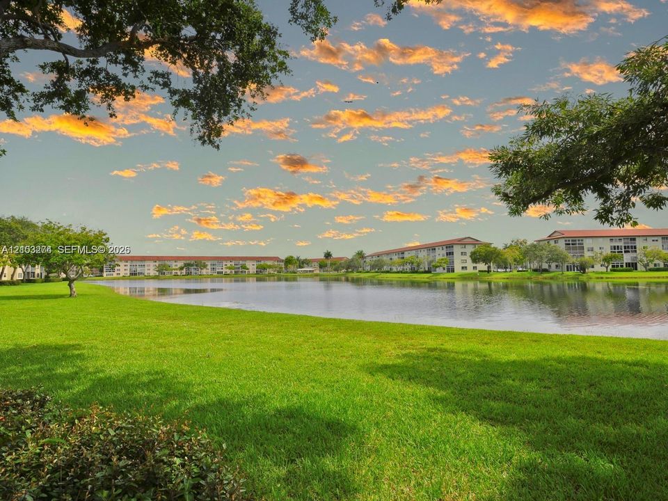Waterfront grounds featuring a sprawling lawn, mature trees, and a lake