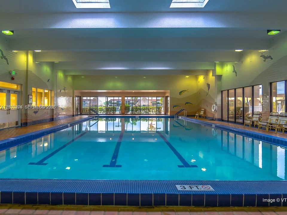 Indoor lap pool featuring a tiled perimeter, skylights, recessed lighting, and floor-to-ceiling glass wall panels