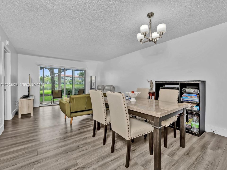 Wood-finish flooring, four-arm chandelier, and sliding glass doors with exterior patio access