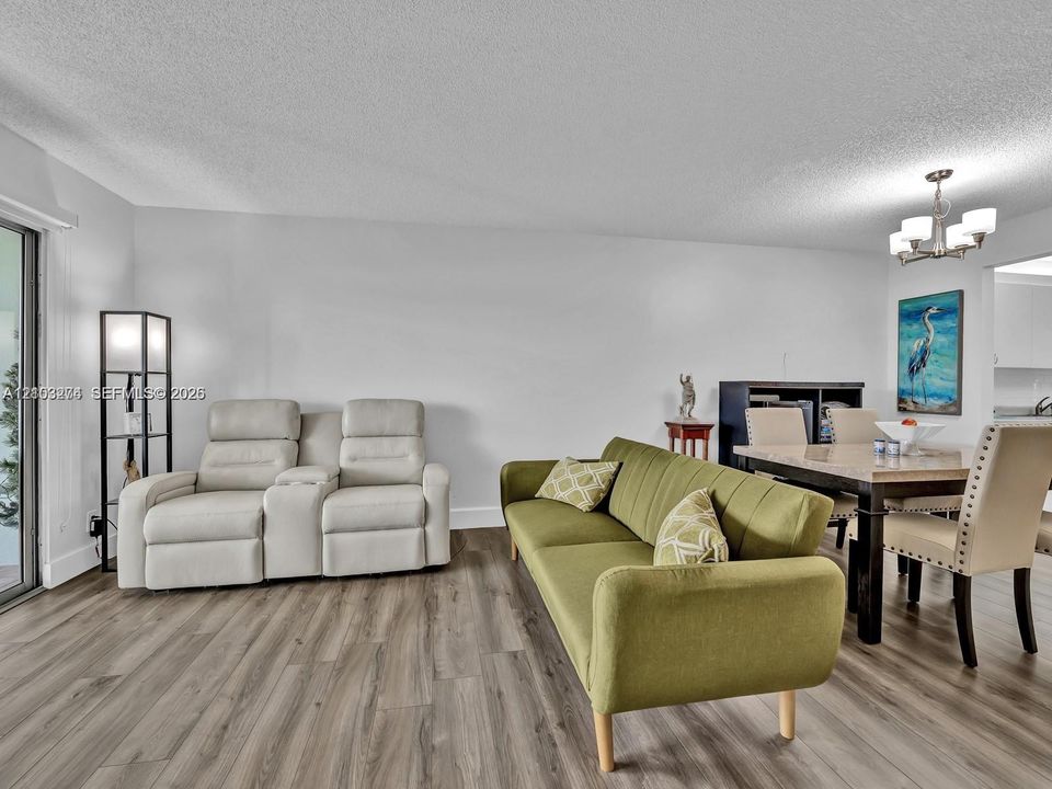 Living space featuring wood-finish flooring, a sliding glass door, and a multi-arm chandelier