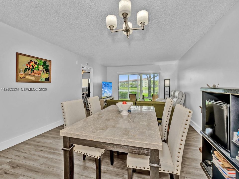 Dining space featuring wood-finish flooring, a multi-bulb brushed-nickel chandelier, and sliding glass doors with exterior water scenery
