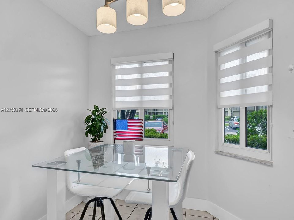 Corner space featuring large windows with tiered light-filtering shades, tile flooring, and a modern three-pendant light fixture