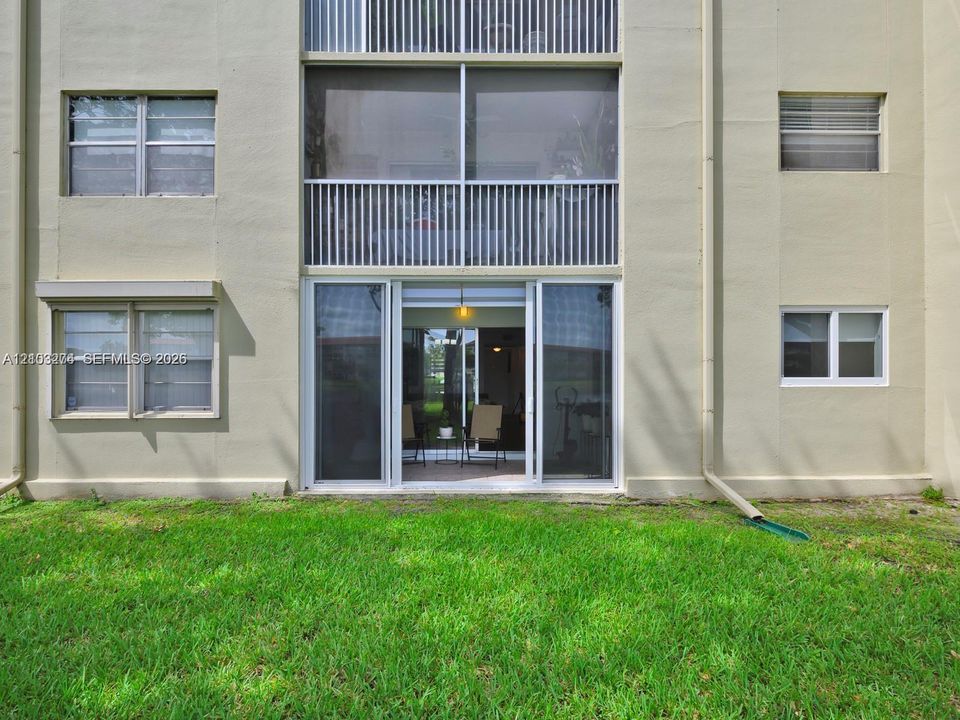 Multi-story exterior featuring a screened balcony with white railings, sliding glass doors, and horizontal-sliding windows