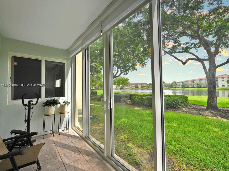 Enclosed patio featuring ceramic tile flooring, floor-to-ceiling glass sliding doors, and windows with integrated screens