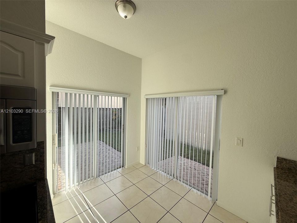 Dual sliding glass doors, neutral tile flooring, and high ceilings