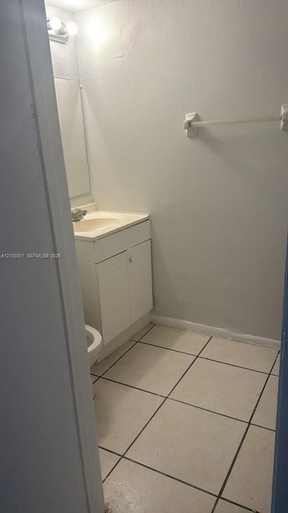 Bathroom featuring a white vanity cabinet with an integrated basin, wall-mounted light fixture, and tile flooring