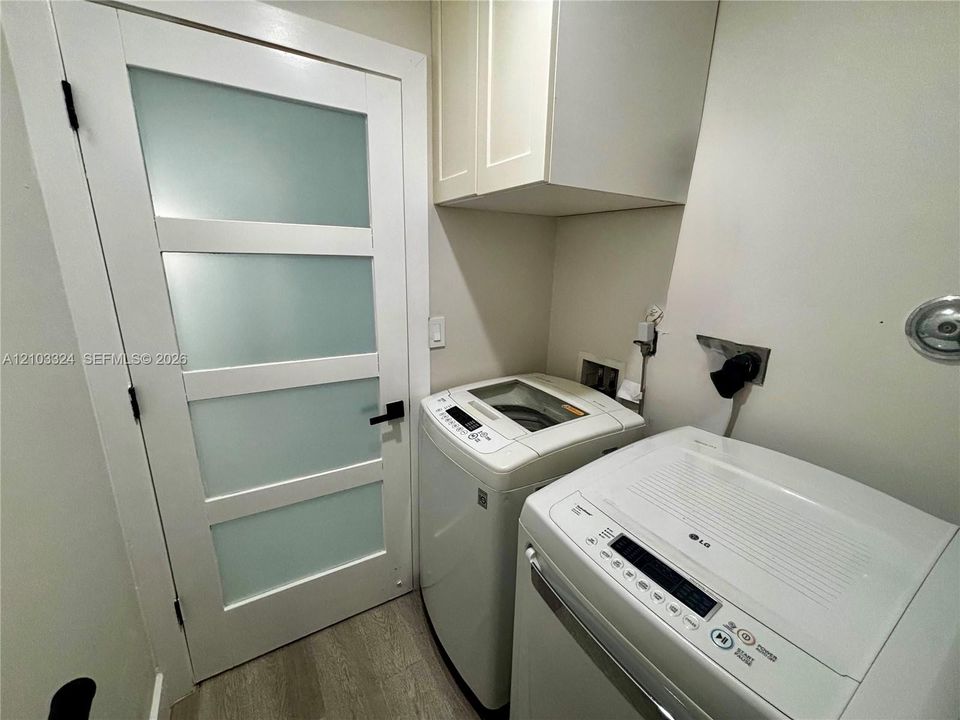 Shaker-style upper cabinetry, wood-finish flooring, and a solid-core door featuring four frosted glass panels with matte black hardware