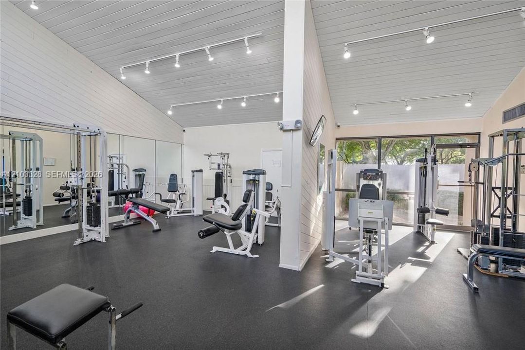 Vaulted ceilings with exposed beams, track lighting, full-wall mirrors, and durable flooring