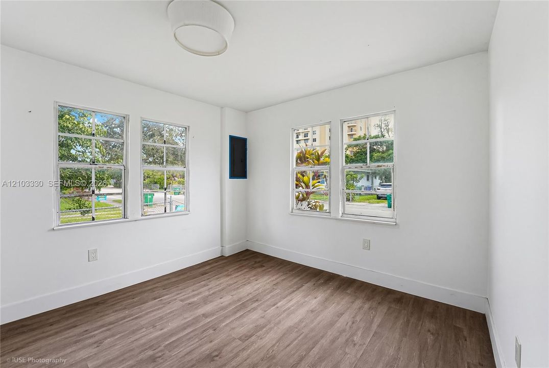 Neutral interior featuring wood-finish flooring, four multi-pane windows, and a circular flush-mount ceiling fixture