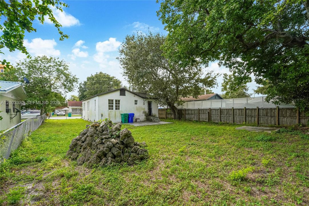 Expansive backyard featuring a lawn, mature trees, and a wooden privacy fence