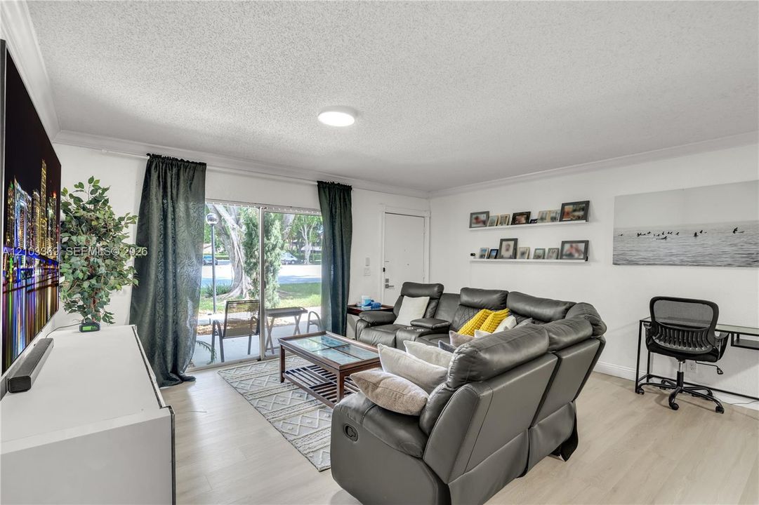 Wood-finish flooring throughout, with a sliding glass door leading to an outdoor patio space