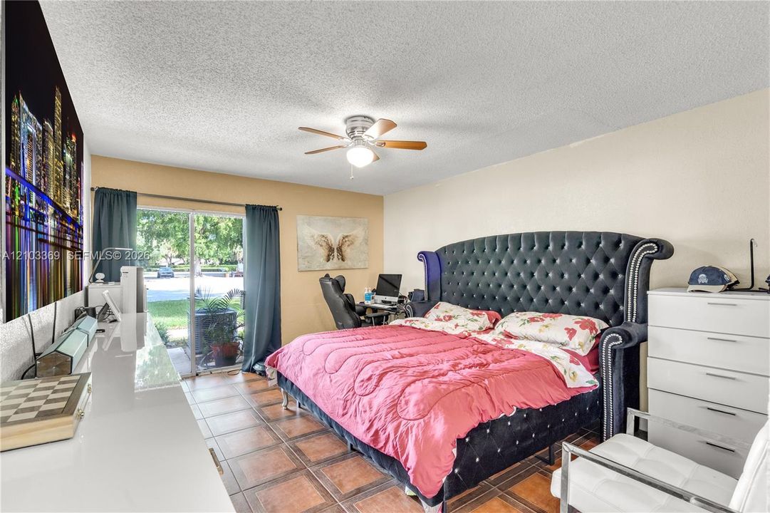 Room featuring ceramic tile flooring, a ceiling fan with light fixture, and a sliding glass door providing external access