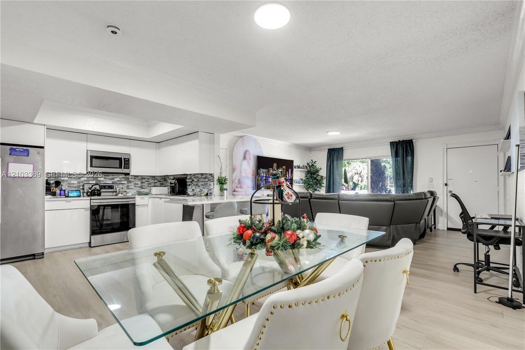 Open-concept living area with wood-finish flooring, recessed lighting, and a kitchen featuring stainless steel appliances and white cabinetry