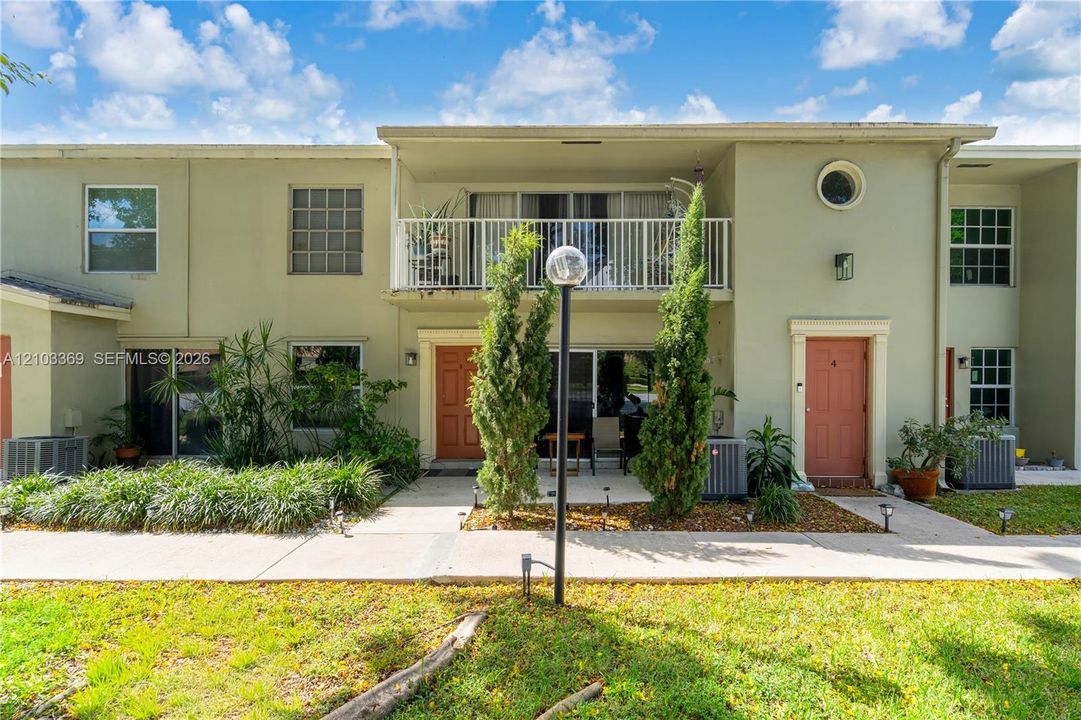 Multi-unit dwelling with light green exterior and a second-story balcony featuring white railings