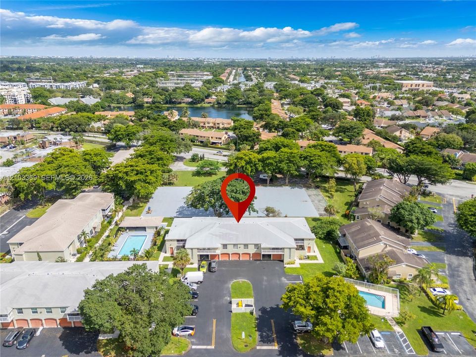 Aerial perspective showcasing multiple residential structures, a community swimming pool, and dedicated parking areas
