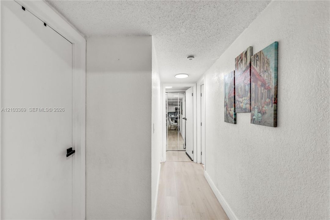 Hallway featuring wood-finish flooring, white walls, and recessed lighting