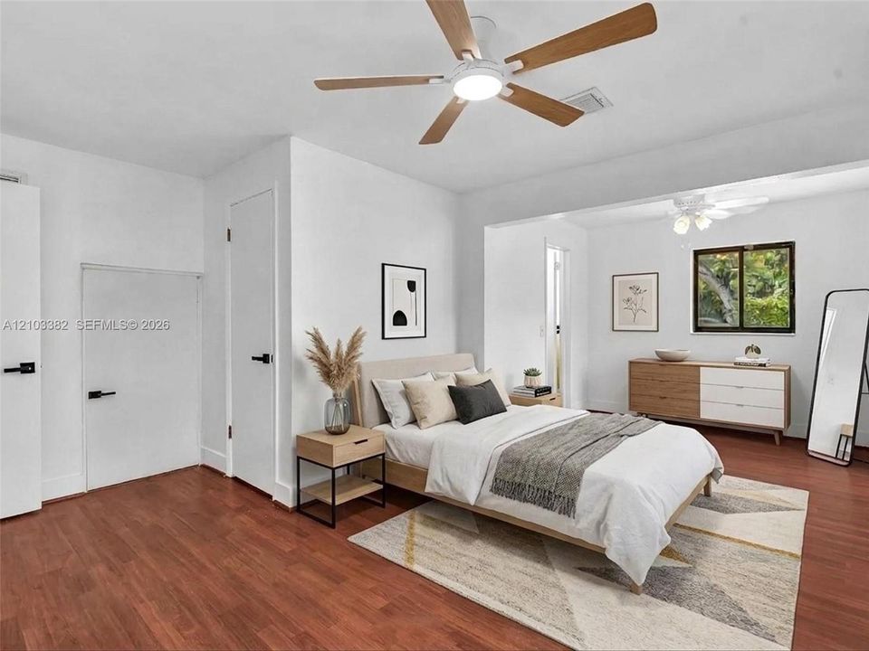 VIRTUAL STAGING. Rear private bedroom featuring walk-in closet, en-suite bath, siting area and wood-finish flooring, white doors with matte black hardware, dual ceiling fans, and nice windows. House for rent in Coral Gables. House for rent listed by Realtor.