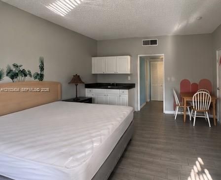 Interior space featuring wood-finish flooring, white cabinetry with dark countertops, and a built-in sink