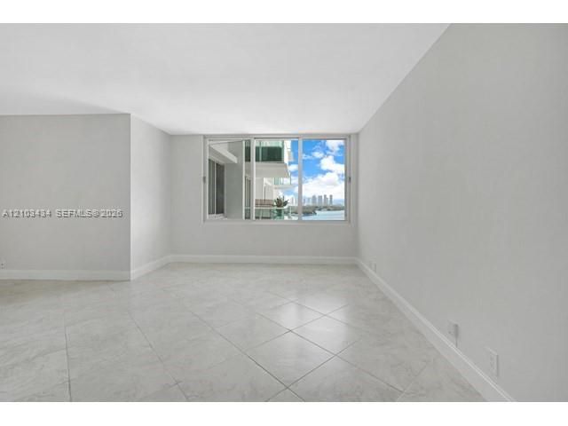 Neutral-toned interior space featuring large-format tile flooring, expansive window paneling, and natural light
