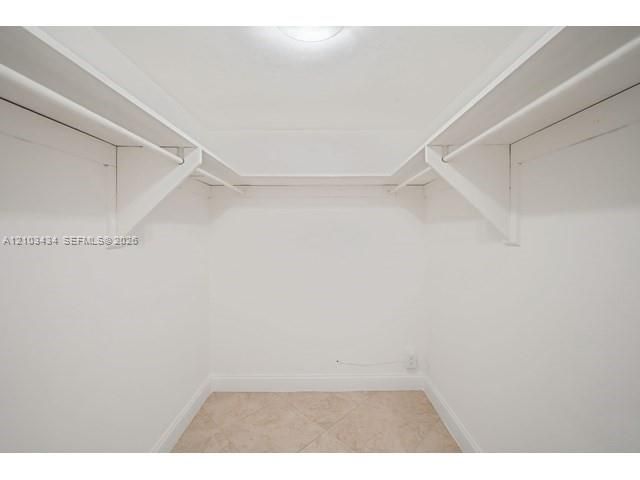 Walk-in closet featuring stone-finish floor tiling, wrap-around shelving, and integrated garment rods