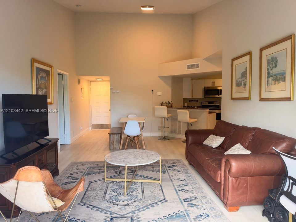 Vaulted ceilings featuring a neutral paint palette, wood-finish flooring, and a breakfast bar with stone-surface countertop
